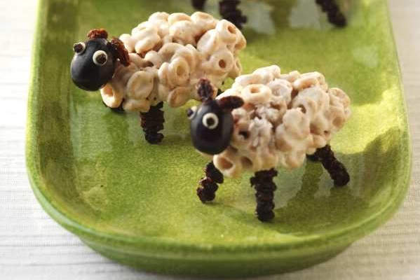 Edible fluffy sheep made from cereal, marshmallows, black grapes and raisins.